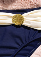 Biquíni Océan Naval Alizée, azul-marinho com drapeado off-white, concha dourada e top push-up. Elegante, cintura alta e perfeito para férias à beira-mar.