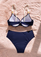 Biquíni Océan Naval Alizée, azul-marinho com drapeado off-white, concha dourada e top push-up. Elegante, cintura alta e perfeito para férias à beira-mar.
