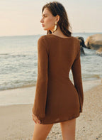 Saída Flavia, vestido curto em tricô castanho, decote gota preso por estrela do mar dourada e mangas longas. Chic, semi-transparente e perfeita para resorts.
