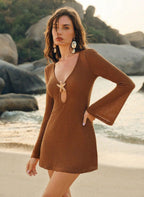 Saída Flavia, vestido curto em tricô castanho, decote gota preso por estrela do mar dourada e mangas longas. Chic, semi-transparente e perfeita para resorts.