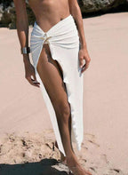 Saia de praia Étoile Ellie, tecido plissado semi-transparente, fenda lateral profunda e estrela do mar dourada. Preto e cáqui para um look resort luxuoso.