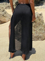 Saída de Praia Lucie, tecido viscose preto, fenda lateral sensual, estrela do mar dourada e nó divisor. O luxo boho para transitar da praia ao resort com elegância.