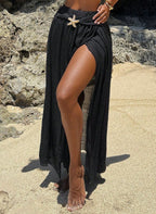 Saída de Praia Lucie, tecido viscose preto, fenda lateral sensual, estrela do mar dourada e nó divisor. O luxo boho para transitar da praia ao resort com elegância.