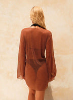 Saída Capucine, vestido solto em malha castanho, decote V profundo, mangas compridas e brilho metálico. Elegância fluida para praia, resort e férias.
